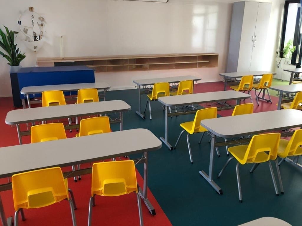 Classroom of two-seater desks with yellow shell chairs facing a whiteboard — interior concept
